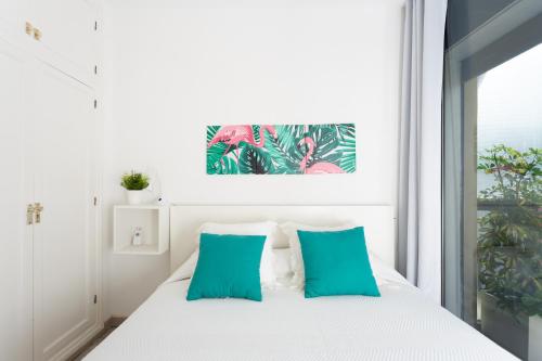 ein Schlafzimmer mit einem weißen Bett mit blauen Kissen in der Unterkunft Monkey house in Santa Cruz de Tenerife