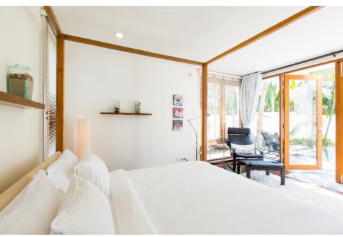 1 dormitorio con 1 cama blanca y 1 silla en Pranaluxe Pool Villa Holiday Home, en Pran Buri