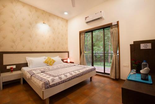 a bedroom with a bed and a large window at SaffronStays Dhyana, Vikramgad in Pālghar