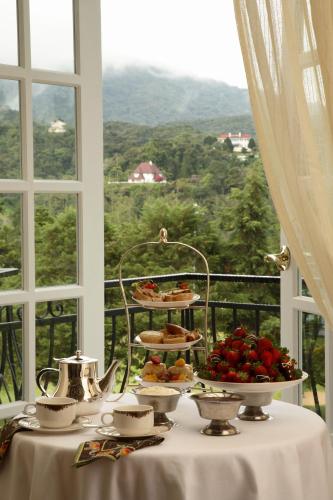 a table with plates of food on a table with a window at Cameron Highlands Resort - Small Luxury Hotels of the World in Cameron Highlands