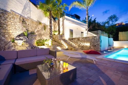 a patio with a couch and a swimming pool at Villa Zagara Garden Spectacular Sea View in Taormina in Taormina