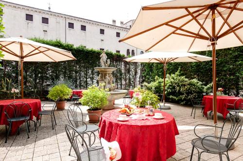 eine Terrasse mit Tischen, Stühlen und Sonnenschirmen in der Unterkunft Hotel Belle Arti in Venedig