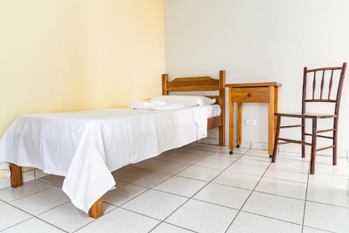 a bed in a room with a table and a chair at Eventos & Hospedagem Sagrada Família in Sao Paulo
