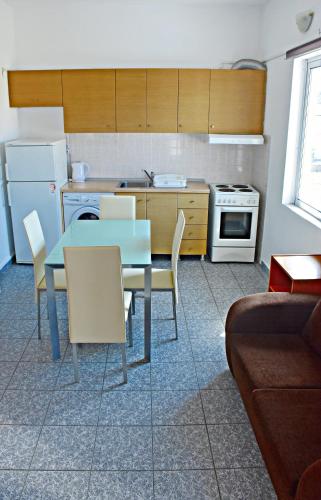 a kitchen with a table and chairs and a kitchen with a refrigerator at Vicky Studios in Myrina