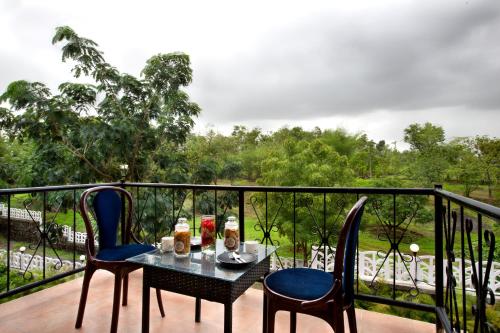 a table and two chairs on a balcony at SaffronStays Nithyam, Vikramgad in Pālghar