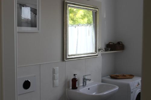 un bagno bianco con lavandino e finestra di rosmarin-am-sund ad Altefähr