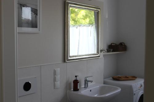 a white bathroom with a sink and a window at rosmarin-am-sund in Altefähr