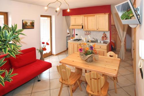 a kitchen and living room with a wooden table and a red couch at Casa Stella in Falcade
