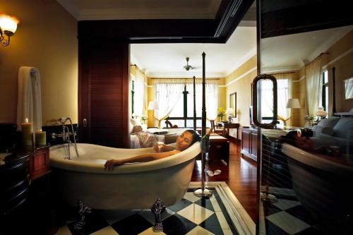 Eine Frau, die in einer Badewanne im Bad liegt. in der Unterkunft The Majestic Malacca Hotel - Small Luxury Hotels of the World in Malakka