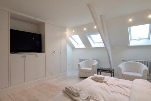 een slaapkamer met een bed en twee stoelen en een televisie bij Cap's House in Gent