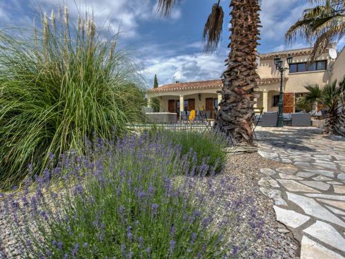 Félines-MinervoisにあるModern villa with private poolの家の前のヤシの木と紫の花