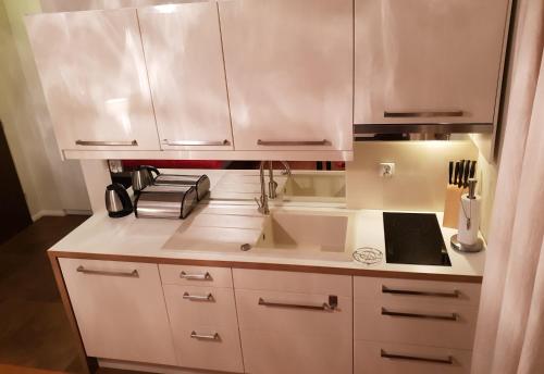 a kitchen with white cabinets and a sink at Lux Apartment Cosy in Polanica-Zdrój