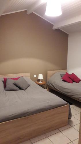 Saint-Père-en-RetzにあるLe Bois Regnierのベッドルーム1室(赤い枕のベッド2台付)