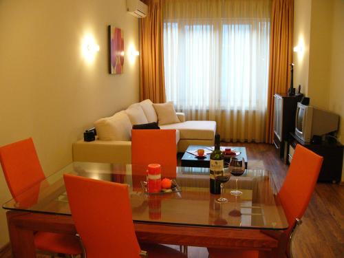 شقق في آي بي صوفيا في صوفيا: غرفة معيشة مع طاولة وكراسي برتقالية
