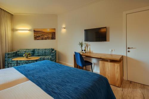 a hotel room with a bed and a desk and a couch at Kinar Galilee in Kinar
