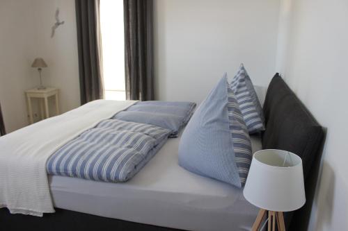 Una cama con almohadas azules y blancas y una lámpara. en rosmarin-am-sund, en Altefähr