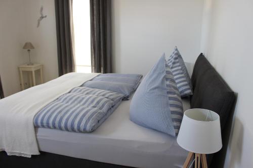 a bed with blue and white pillows and a lamp at rosmarin-am-sund in Altefähr