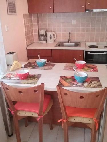 a kitchen counter with two chairs and bowls on it at Nice & Quiet Apartment in Best Area in Alexandroupoli