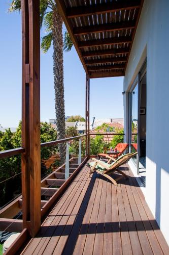 a wooden deck with chairs and a palm tree at The One 8 Hotel in Green Point - Solar Power in Cape Town