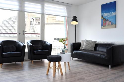 a living room with two black chairs and a couch at Residence Le Mistral in Noordwijk aan Zee