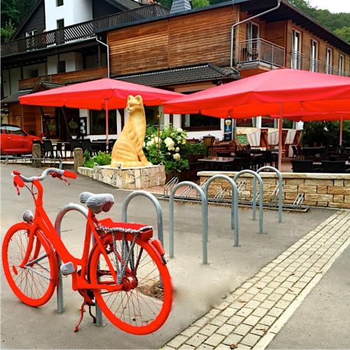 ein Fahrrad, das vor einem Restaurant mit einer Katzenstatue parkt in der Unterkunft Hotel Roter Kater in Kassel