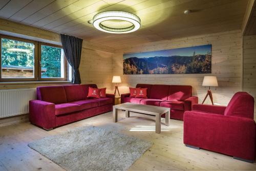 a living room with two red couches and a table at Hotel Björnson & Björnson TREE HOUSES Jasná in Demanovska Dolina