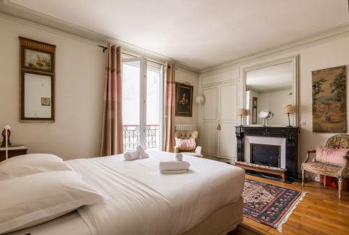 - une chambre avec un grand lit blanc et une cheminée dans l'établissement Veeve - Charming Mirabeau, à Paris