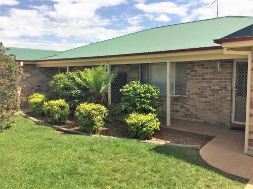a house with a green roof and some bushes at Tic Tac Toe Quality Accommodation in Armidale