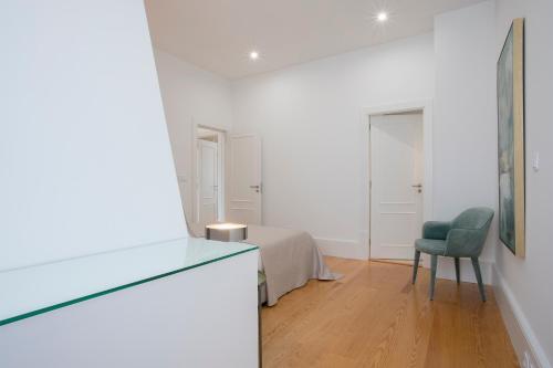 a white room with a bed and a chair at Liiiving In Porto | Downtown Luxury Apartments in Porto
