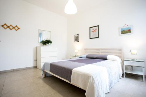 a white bedroom with a large bed and two tables at Sunset Holiday House in Torre Lapillo