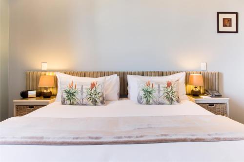 1 dormitorio con 1 cama blanca y 2 lámparas en The One 8 Hotel - Solar Powered, en Ciudad del Cabo