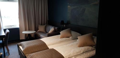 a bedroom with a large bed and a couch at Hotell Maritim Skjervoy in Skjervøy