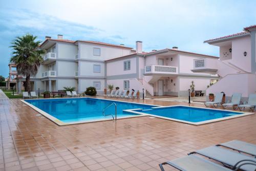 a swimming pool in front of a villa at Stunning Caravelas Apartment in Casal da Lagoa Seca