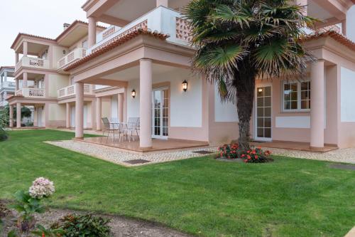 a large house with a palm tree in the yard at Stunning Caravelas Apartment in Casal da Lagoa Seca