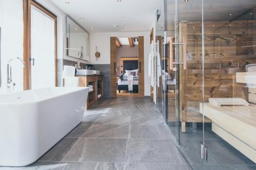 ein Badezimmer mit einer weißen Badewanne und einer Glaswand in der Unterkunft PUR Suites & Chalets in Lermoos