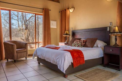 une chambre avec un lit, une chaise et une fenêtre dans l'établissement Warthogs Rest, à Hoedspruit