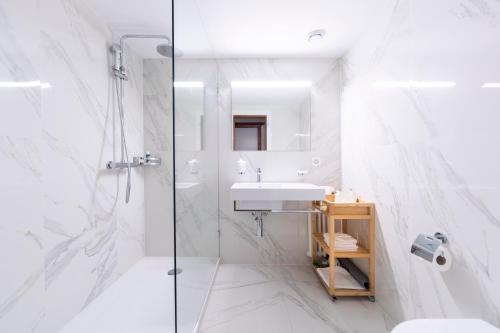 a white bathroom with a sink and a shower at Eden Hotel und Restaurant in Ilanz