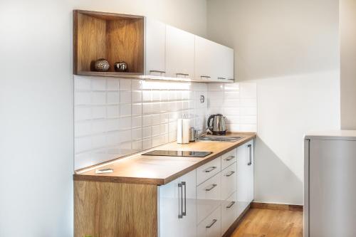 a kitchen with white cabinets and a wooden counter top at SOLAVO HOME&TRAVEL in Solec-Zdrój