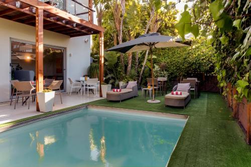 a pool with chairs and an umbrella next to a house at The One 8 Hotel in Cape Town