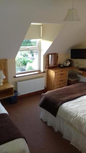 a room with two beds and a window and a desk at Ashfield B&B in Kenmare