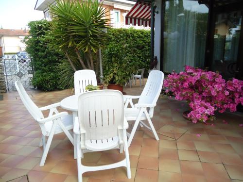 three white chairs and a table on a patio with flowers at Hotel Matilde in Marina di Massa