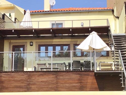 una casa con balcone attrezzato con ombrellone e sedie di Misericórdia Garden Homes a Vila do Conde
