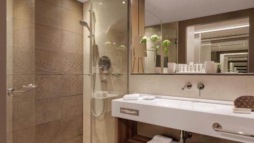 a bathroom with a sink and a shower and a mirror at Hotel Stadt Lörrach in Lörrach