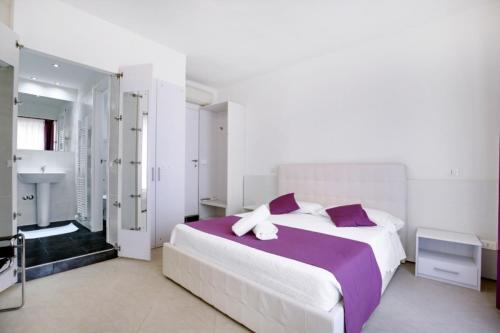 Un dormitorio blanco con una cama grande con almohadas moradas en Fenix La Bohéme, en Venecia