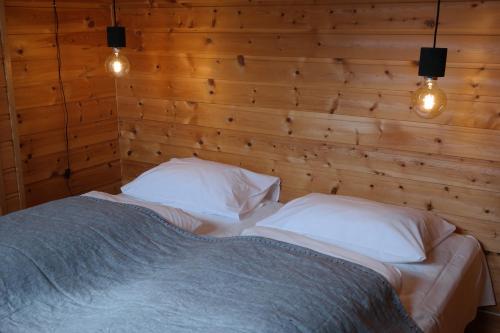 a bedroom with a bed with two pillows and lights at Blåtind Apartments in Stordal