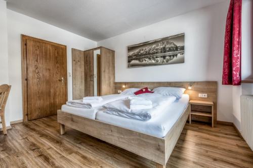 - une chambre avec un grand lit et du parquet dans l'établissement Au Pension, à Söll