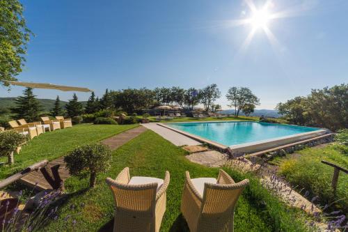 a swimming pool in a yard with chairs in the grass at Villa Di Capovento in Castellina in Chianti