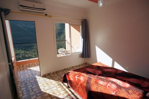 um quarto com uma cama e uma grande janela em Auberge BAB IMOUZER em Tagherat Anekrim