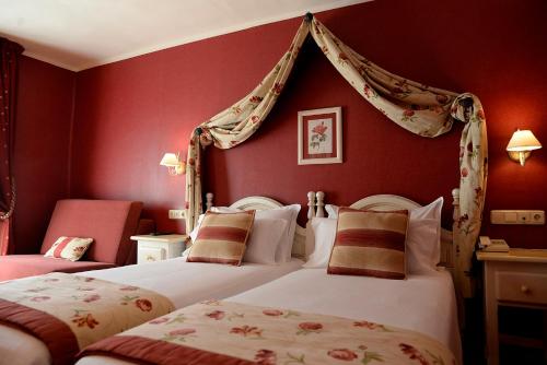 two beds in a room with red walls at Hotel Pradas Ordesa in Broto
