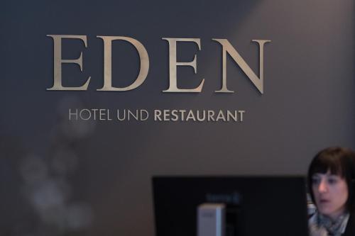 a woman standing in front of a computer in front of a sign at Eden Hotel und Restaurant in Ilanz